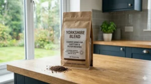 A breakfast setting with a cafetière, a mug of black coffee, and a plate of buttered toast on a kitchen island.