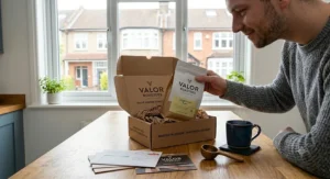 Alt text for image 8: A man sitting in a green armchair by a window in a UK home, holding a Valor Roasters mug, viewing a digital sustainable lifestyle map on a tablet.
