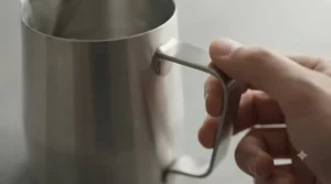 Comfortable, heat-resistant ergonomic handle on a stainless steel milk jug.