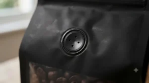 Close-up of a one-way degassing valve on a black matte resealable coffee pouch.